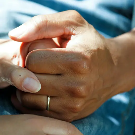 One person holding another person&rsquo;s hands in reassurance