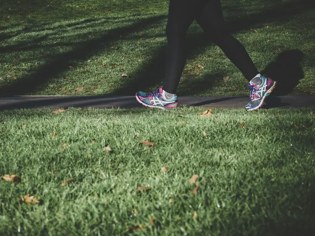 Person in running shoes walking along a park path in morning light